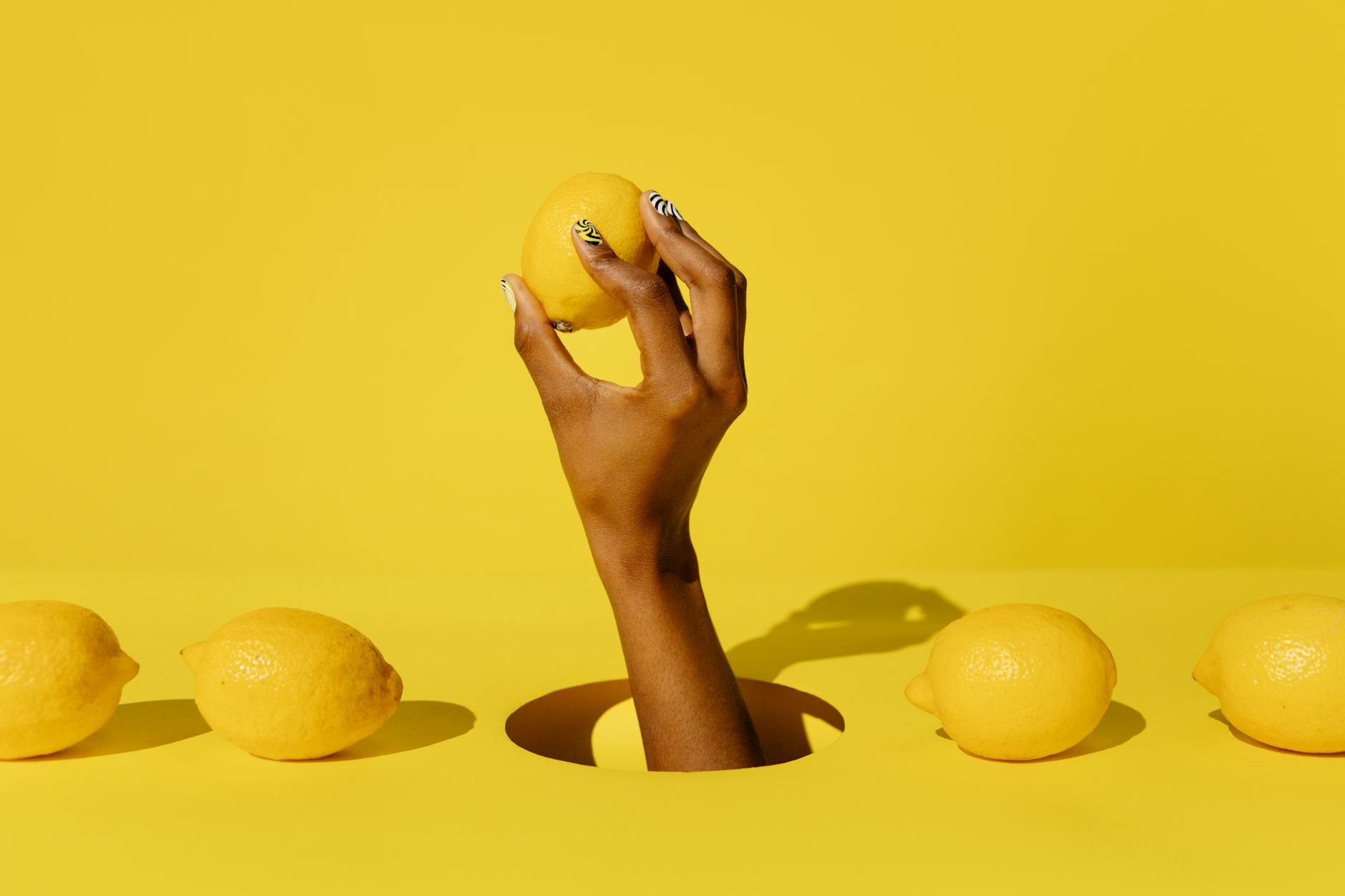 Une main tenant un citron frais sur un fond jaune éclatant, symbolisant la revitalisation et le renouvellement du désir