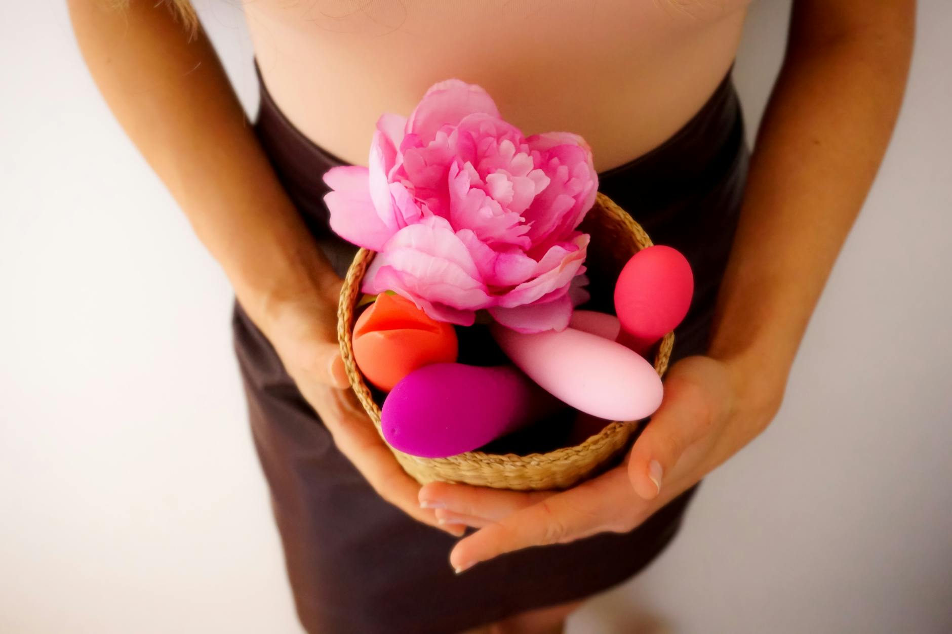 Panier contenant des vibromasseurs colorés et des fleurs roses